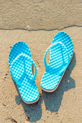 Fototapeta na wymiar Blue flip flops on sand beach. Summer vacation concept