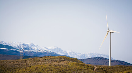 green energy wind turbine with snow-capped mountains in the background