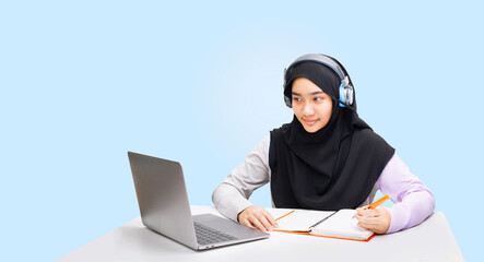 A Muslim girl uses a laptop caomputer for online learning.