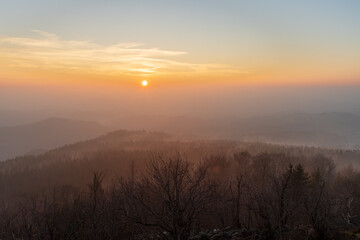 peaks of lusatian mountains in Czech Republic during foggy sunset in winter as seen from mount Hochwald in Germany