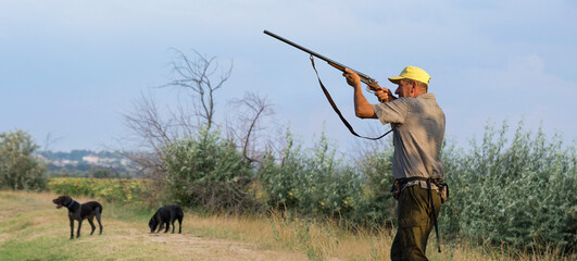Hunter man in camouflage with a gun during the hunt in search of wild birds or game. Autumn hunting season.