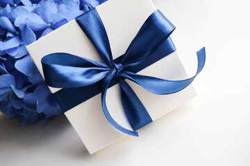 romantic composition of blue flowers on white background and gift box with blue bow