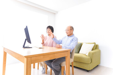 Fototapeta premium パソコンでテレビ電話をする高齢の夫婦