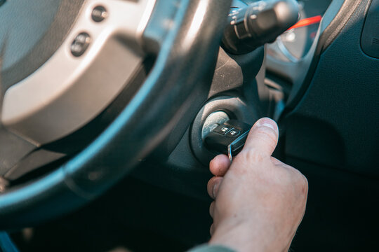 close up man hand put key to start car engine