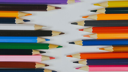 Many colored pencils are arranged around the edges of the image as a frame. In the center is an empty background with space for text. Mock up with copy space.