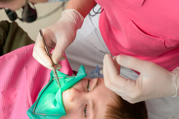 The dentist treats the child's tooth using a rubber dam.