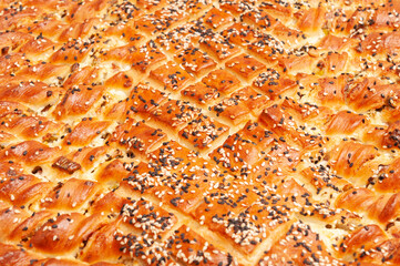 salty pie of puff pastry sprinkled with sesame on a wooden background