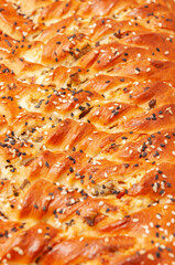 salty pie of puff pastry sprinkled with sesame on a wooden background