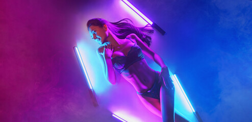 beautiful girl in neon light lies on the floor. Mixed Colorful Light Concept.
