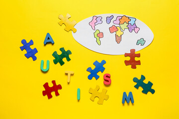 Drawn world map and colorful puzzle pieces with word AUTISM on color background