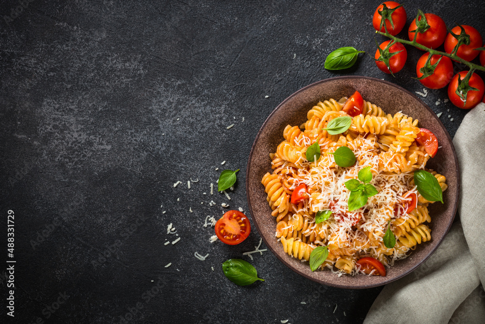 Sticker italian pasta alla arrabiata with basil and parmesan cheese on dark table. fusilli pasta with tomato