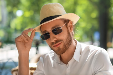 Portrait of handsome young man in stylish hat outdoors