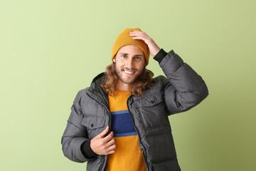 Handsome young man in warm clothes on color background