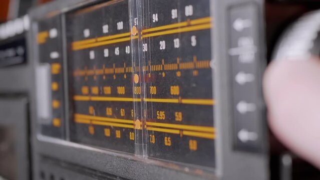 Female Fingers Adjusting the Frequency on an Old Vintage Analog Receiver. Search for a music radio station on a dial scale on panel of a short-wave portable FM radio, player, tape recorder 80s, 90s.