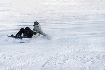 A young man without a protective helmet and goggles falls on a snowboard. Concept: violation of...
