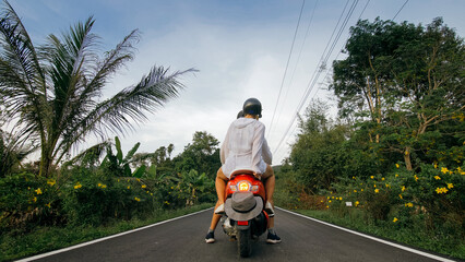 Love couple on red motorbike in white clothes to go on forest road trail trip. Two caucasian...