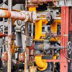 Pipes, connections, stopcocks and turning wheels in apparent chaos in confusing arrangement in an industrial plant