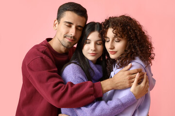 Man and two beautiful women on color background. Polyamory concept