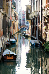 Fototapeta na wymiar Kanal mit Gondeln in Venedig mit Brücke im Hintergrund