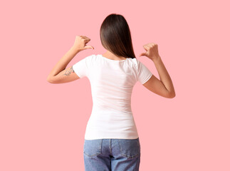 Young woman in blank t-shirt on color background, back view