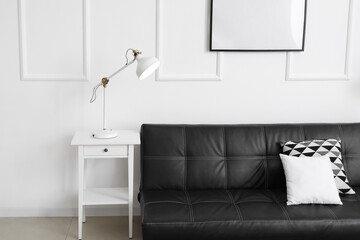 Glowing white lamp on table and sofa near light wall