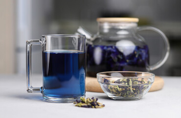 Glass cup of organic blue anchana. Brewed tea in a transparent glass teapot on a gray table. Herbal Thai tea. Selective focus
