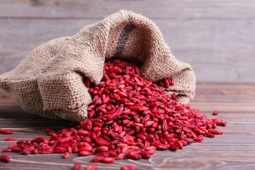 Bag with dried barberries on wooden background