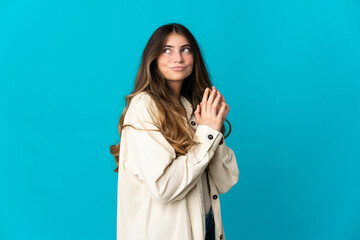 Young caucasian woman isolated on blue background scheming something