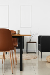 Interior of light dining room with table and black armchairs