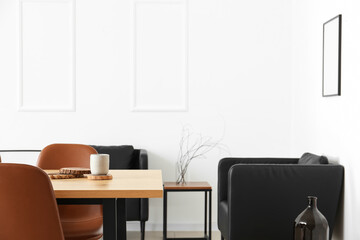 Interior of light dining room with table and black armchairs