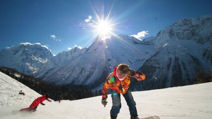 Happy snowboarder showing tricks on ski slope and showing thumbs up