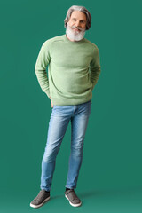 Handsome senior man in knitted sweater on green background