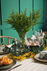 Dining table with beautiful setting near green wall