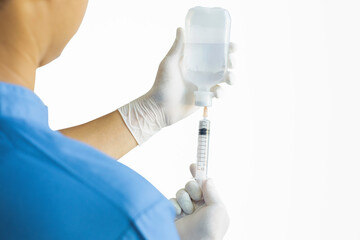 Hands of a doctor or nurse wearing rubber gloves and using a syringe to suck Sodium Chloride in a clinic or hospital alone with a white background.
