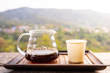 Hot arabica coffee and paper cup  on wooden table in the morning with mountain background.