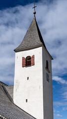 Fototapeta na wymiar La Crusc. The bell tower of the church. Typical Tyrolean church tower. General context. Badia, Alto Adige, South Tyrol, Italy