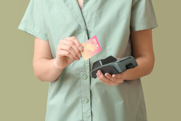 Beautiful young woman with payment terminal and credit card on green background, closeup