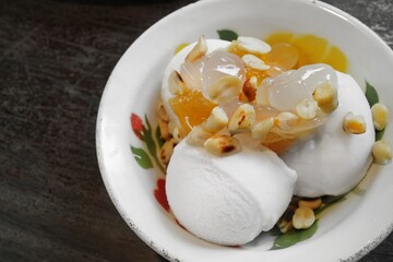 Thai style coconut ice cream topping with roasted peanuts, sweet pineapple and  sweet palm kernels, serving on vintage enamelware