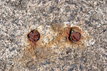 Old Rusted Fixings Set in Rough Stone Block  in Close Up 