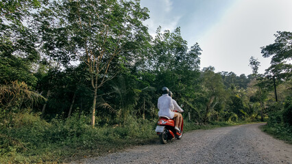 Love couple on red motorbike in white clothes to go on forest road trail trip. Two caucasian tourist woman man drive on scooter. Motorcycle rent, safety helmet, sunglasses. Asia Thailand ride tourism.