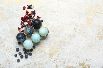 Holder with beautiful Easter eggs, blueberry and dried hibiscus on light background