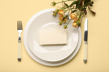 Table setting with blank card and roses on color background