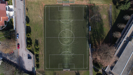 Aerial view of a Sports field in a residential area with artificial green grass and football goal,...