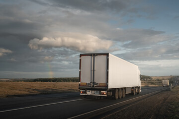 Freight truck under dramatic stormy sky with rainbow