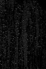 Drops of water flow down the surface of the clear glass on a black background. Vertical placement of the frame. Texture for creativity. - obrazy, fototapety, plakaty