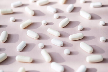 Different pills, vitamin capsules on pastel pink background. Dietary supplement supports for health. - obrazy, fototapety, plakaty