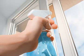 Cleaning. Window glass and hand with detergent spay bottle