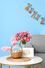 Greeting card with text HAPPY EASTER, eggs and tulips in vase on table in room