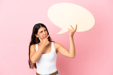 Young caucasian woman isolated on pink background holding an empty speech bubble and thinking