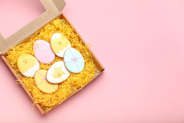 Cardboard box with Easter cookies on color background